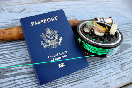 A flyrod and reel rests on a dock with a passportの写真素材
