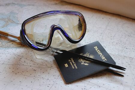 A spearfishing pole and diving mask with passport lie on a nautical chart.の写真素材