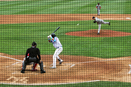 A baseball pitcher delivers a pitch to home plate 