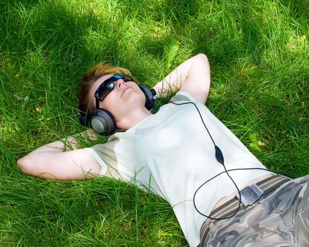 young girl listnening music on a grassの写真素材