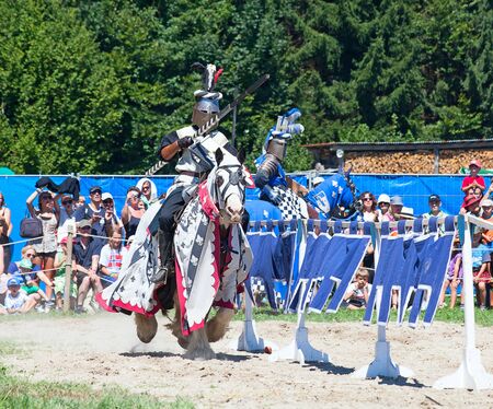 AGASUL, SWITZERLAND - AUGUST 18: Unidentified men in knight armor on the horse riding with spear during tournament reconstruction near Kyburg castle on August 18, 2012 in Agasul, Canton Zurich, Switzerland.のeditorial素材