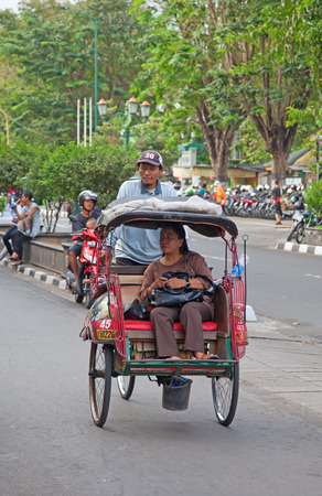 YOGYAKARTA - AUGUST 03: Traditional rikshaw transport on streets of Yogyakarta, Java, Indonesia on August 03, 2010. Bicycle rikshaw remains popular means of transport in many Indonesian cities.のeditorial素材