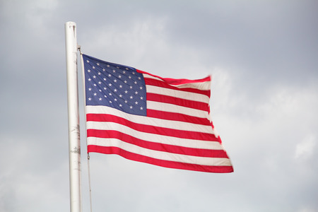 Flag of the United States against dark cloudy skyの写真素材