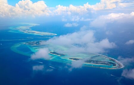 Small island in the Maldives covered by palms and surrounded by turquoise blue waters with with beautiful corals and animals, perfect escape from the cold winterの写真素材
