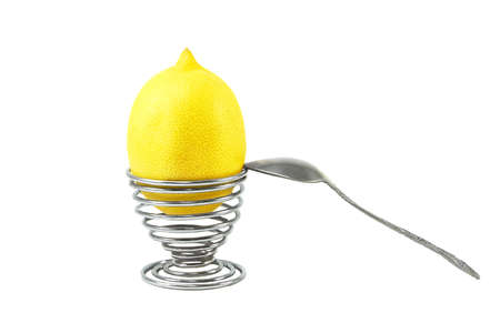 Lemon in the eggcup with spoon on white backgroundの写真素材