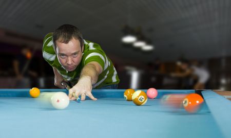 caucasian man playing an eight ball pool game in a pool barの写真素材
