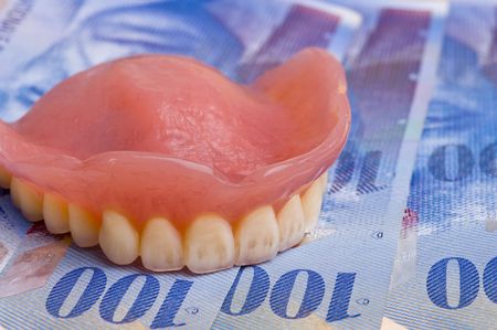 false teeth prosthetic on swiss franc bills with focus on the front teeth