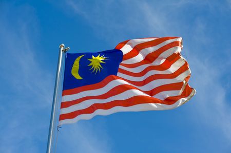 malaysian flag on a pole against blue skyの写真素材