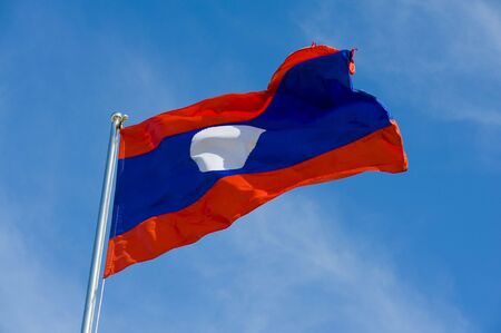 laotian flag on a pole against blue skyの写真素材