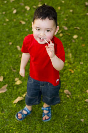 cute, small boy with lollipop in the parkの写真素材