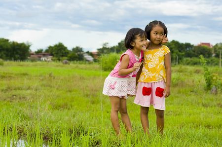 cute girl holding a grasshopper in her hand showing her friend somethingの写真素材