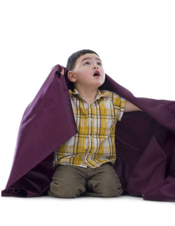 cute boy kneelin in studio looking up, isolated on white backgroundの写真素材