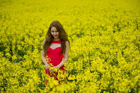 teenager beauty with red dress in canola field 