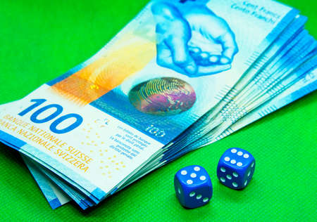 Two blue dices next to money bills with a green backgroundの写真素材