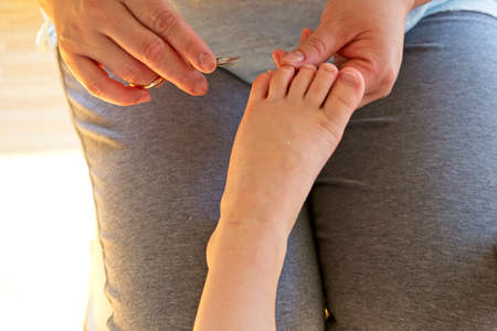 Hands of a woman cutting the toenails of a child
