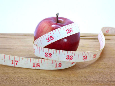 Apple and tape measure on wooden