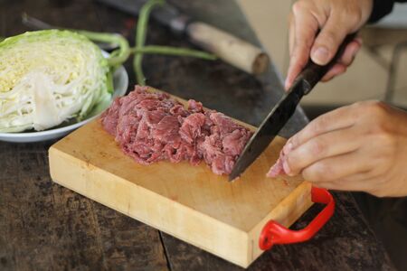 Hand of man cutting meatの写真素材