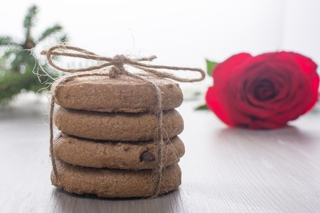 stack of cookies, perevyazanaya twine, lies next to a red rose. Blurred background, bokeh. Romantic picture, breakfast. Festive mood.の写真素材