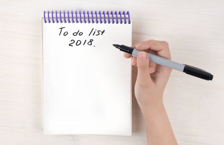 A to-do list in a notepad on spirals. Place for text. A girls hand holds a marker.の写真素材