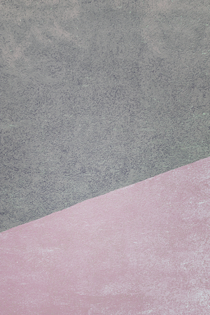 Wall with a texture of plaster, painted in two colors. Pink and gray color on the dioganal. Beautiful background.の写真素材