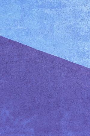 Wall with a texture of plaster, painted in two colors. Blue and violet on a dioganal. Beautiful unusual background.の写真素材