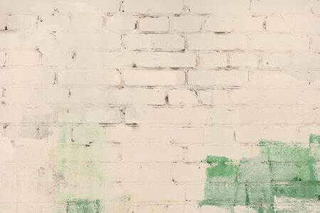 The brick wall is painted abstractly with green and pale beige paint. Background with a divorce, texture.の写真素材