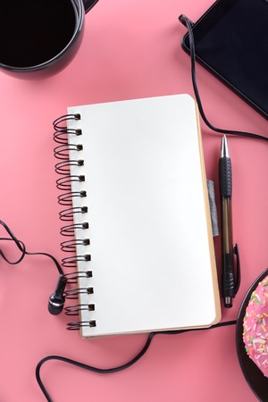 Open notebook on springs with white pages. Tablet, coffee and donuts. Mock up.の写真素材