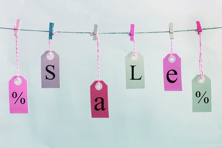 Labels hang on the rope with colored clothespins. They are inscription SALE and a percent sign.の写真素材