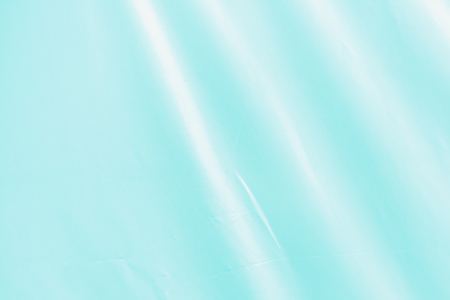 Background with a silk texture. A turquoise fabric with folds.