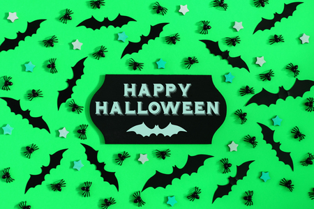 On a light green background, many decorative bats, small stars and spiders are laid out. In the center there is a sign with the inscription of Happy Halloween.の写真素材