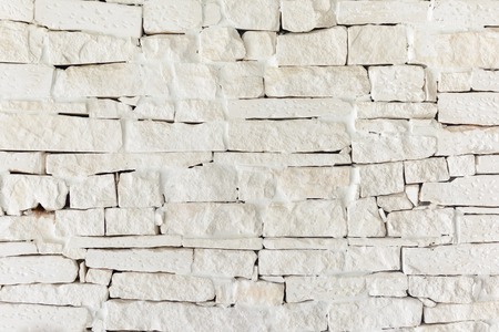 A wall of uneven bricks painted with beige paint.の写真素材