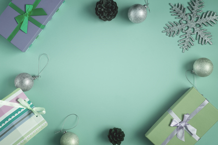 On a green background lie gifts, pine cones and Christmas balls. In the center there is an empty place for an inscription, mock up.の写真素材