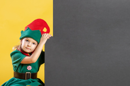 Little girl in an elf costume. Near the child on a black background a place for text, copy space.