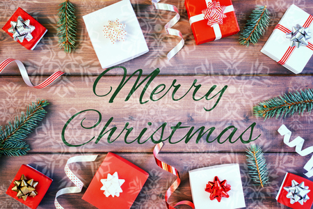 Many small gift boxes, decorative ribbons and Christmas tree branches. In the center on a wooden...