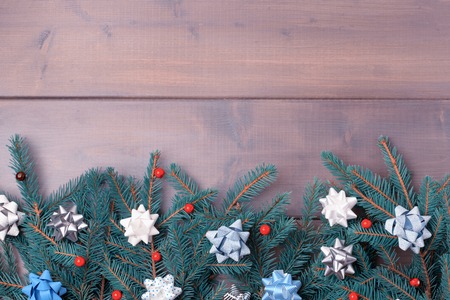 Spruce branches decorated with decorative bows and red berries. Winter composition with copy space on a dark wooden background. Festive layout.の写真素材