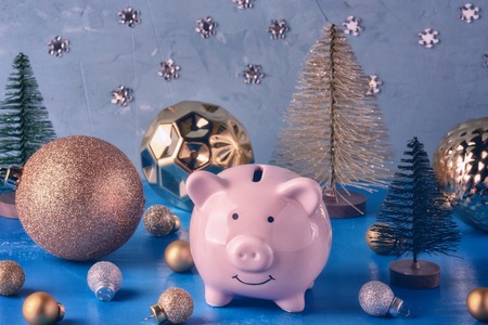 Little pink piggy bank in a magical forest of Christmas balls and decorative Christmas trees.の写真素材