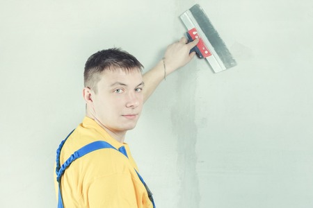 A man in working form, treats the wall with a spatula.の写真素材