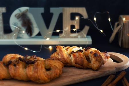 Wicker cake of puff pastry. Delicious dessert with chocolate. In the background the lights garland.の写真素材