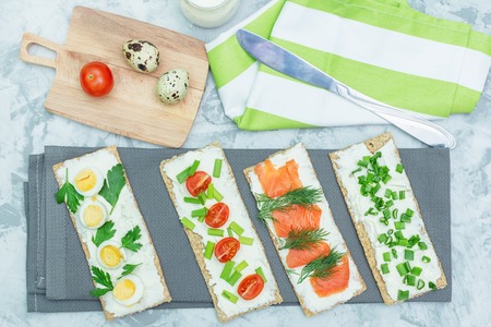Small sandwiches with curd cheese, tomatoes and trout. A light summer snack is cooked on a gray table. Photo above.の写真素材