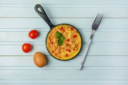Freshly made omelet, Turkish national recipe Menemen with eggs, bell pepper and tomatoes. Photo on a blue background with copy space.の写真素材