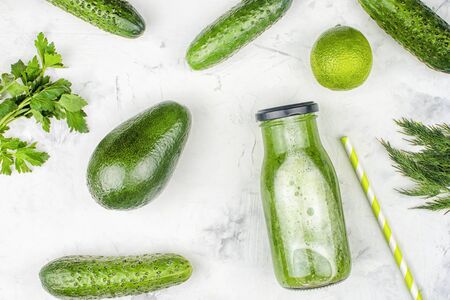 On a light background a bottle with a cucumber smoothie. Freshly squeezed cucumber juice with lime and avocado. Flat lay, ingredients.の写真素材