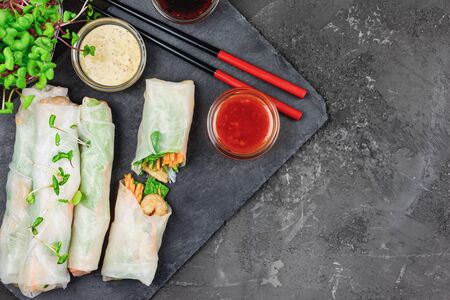 Spring roll with vegetables, shrimp and microgreen radish. A healthy asian snack on a black concrete background. Photo with copy spaceの写真素材
