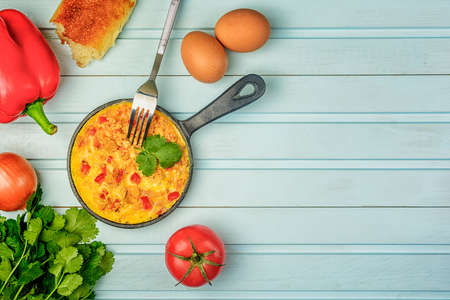Fried eggs with bell pepper and onions. Turkish national omelet, Menemen. Copy space on a blue background, flat lay.の写真素材