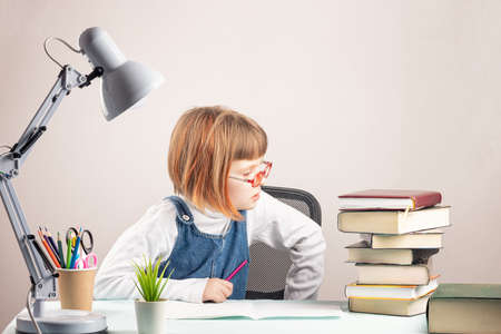 The little girl is attentively examining the stack of books.の写真素材