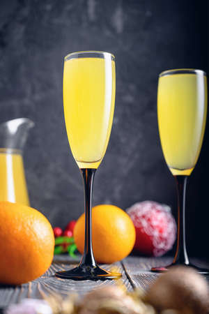 Against a dark background, two glasses with champagne and orange juice. Festive cocktail Mimosaの写真素材