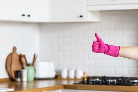 Woman hands wearing protective gloves on white kitchen background. Concept of clean kitchen, successful thumb up yes ok signの写真素材