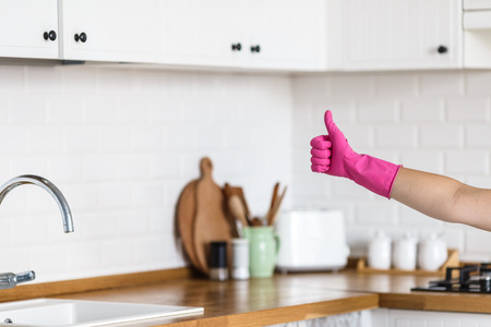 Woman hands wearing protective gloves on white kitchen background. Concept of clean kitchen, successful thumb up yes ok signの写真素材