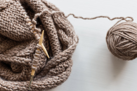 Beige knitting wool and knitting needles on white wooden background. Knitting as a hobby. Accessories for knitting.の写真素材