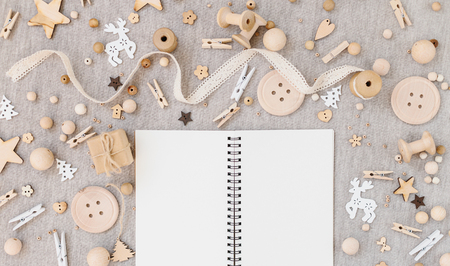 Craft and wooden Christmas flatlay on farbic background. Empty opened notebook, wooden supplies, cotton lace and christmas symbols. Place for textの写真素材
