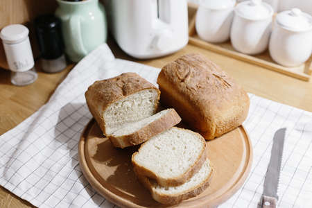 Homemade freshly baked bread on the kitchen wooden table. Dinner preparation